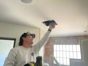 A technician performing pest control services to seal scorpion entry points in a home.