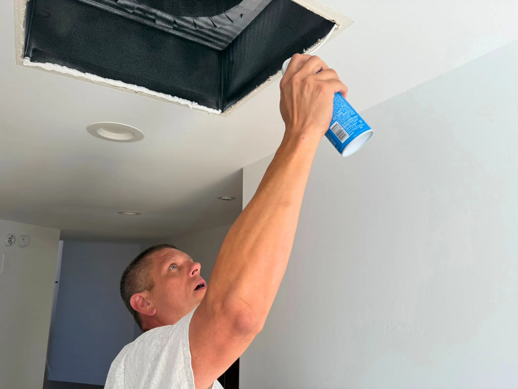 Mike With Blue Can applying spray foam for Building Performance Sealing around a ceiling vent