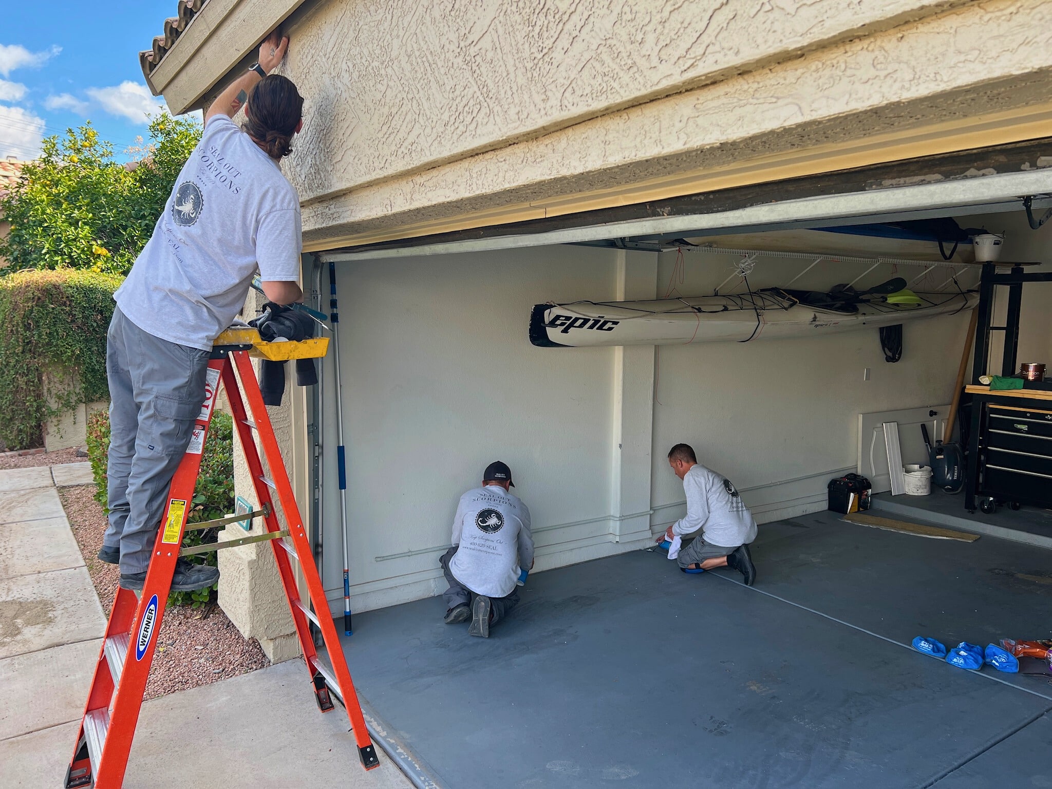 Technicians applying a garage seal to block potential pest entry points