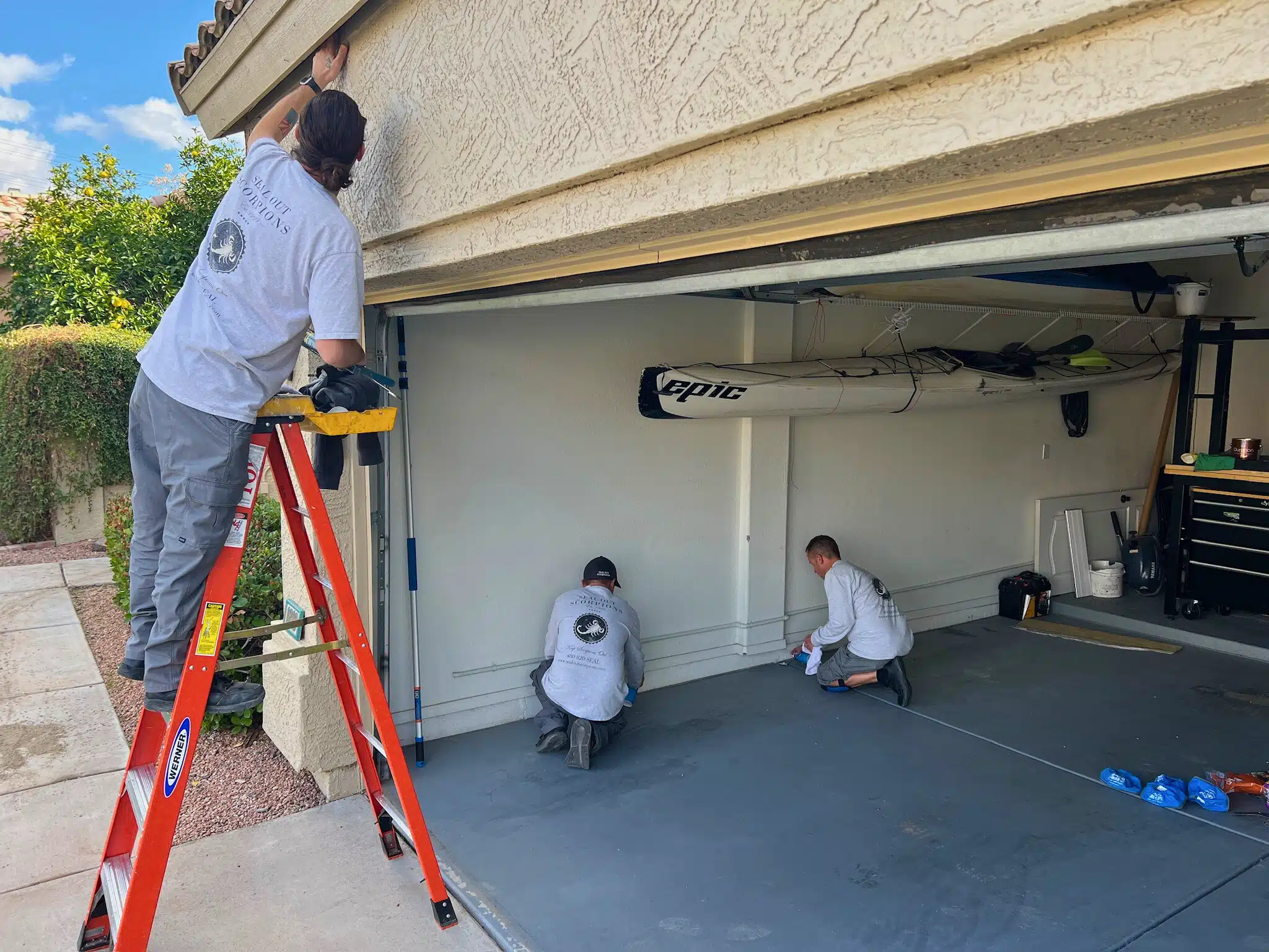 Technicians applying a garage seal to block potential pest entry points