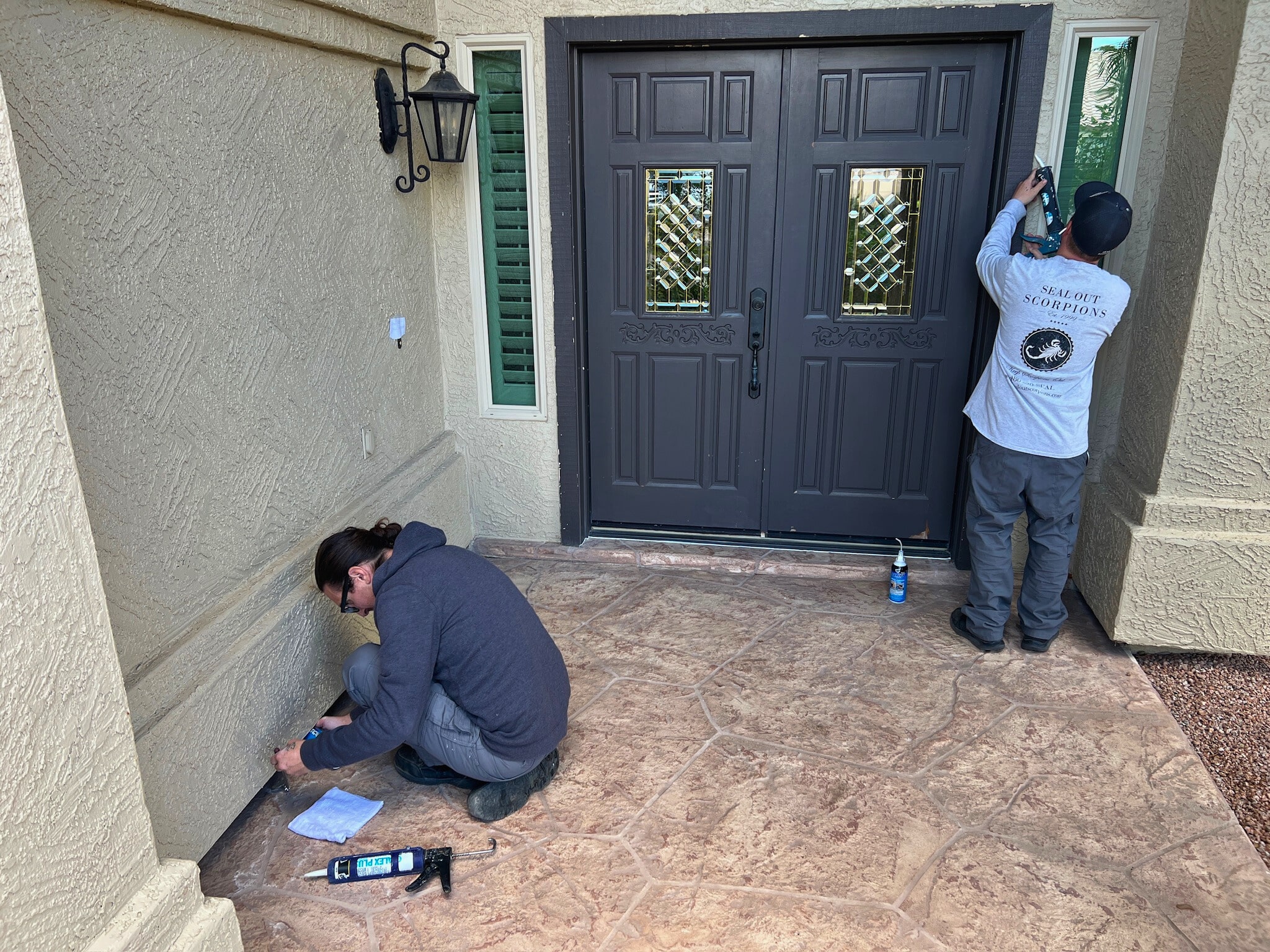 Technicians applying an outside door seal to prevent pests from entering