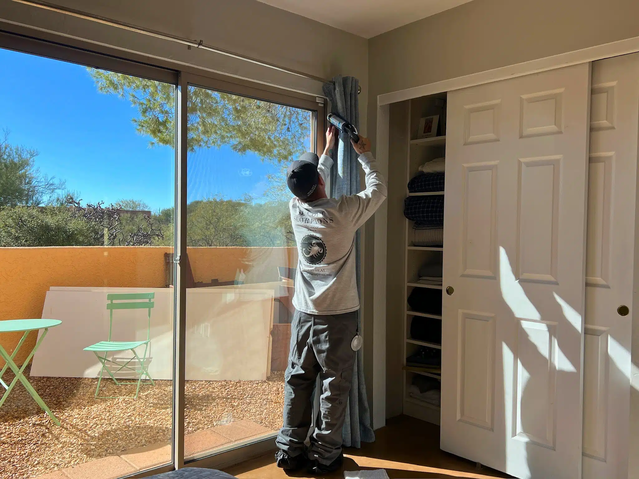 echnician sealing gaps around windows to prevent micro-air leaks and pests like scorpions from entering the home