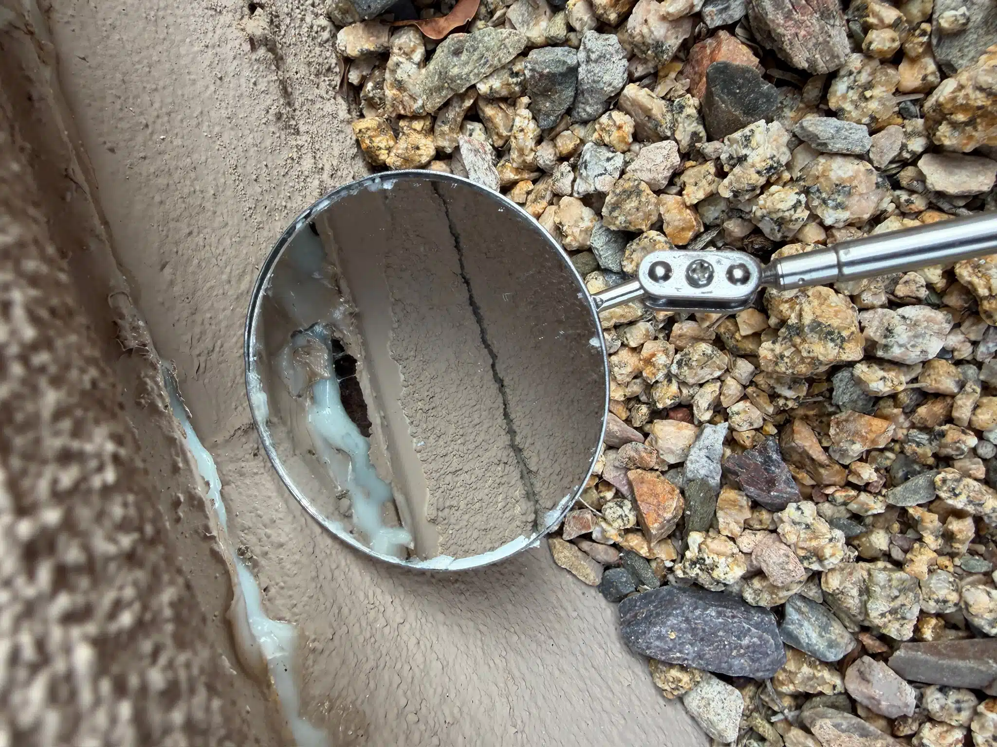 A close-up of a sealing failure around a home's foundation, showcasing gaps and poor material choice during a pest barrier evaluation, revealing ineffective pest control