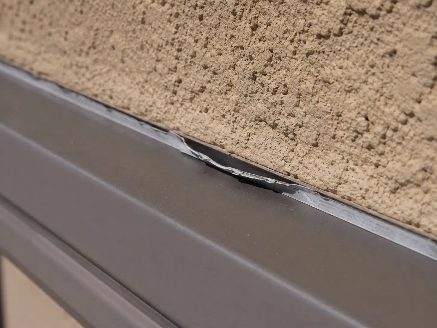 Exterior stucco with heat-damaged sealant highlighting June sealing challenges